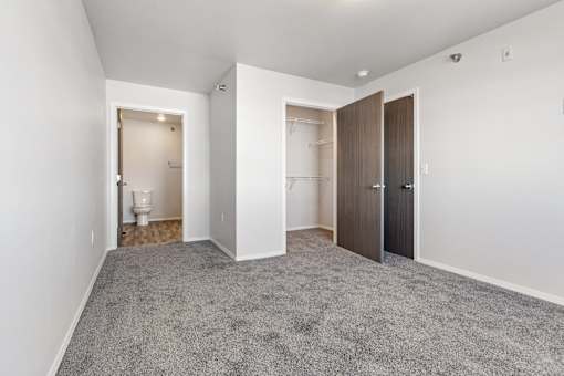 A room with a carpeted floor and two doors.