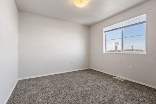 A room with a carpeted floor and a window showing a view of a building outside.