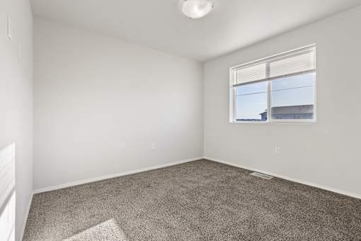 A room with a carpeted floor and a window.