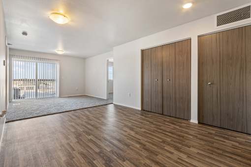 A room with wooden floors and two brown wardrobes.