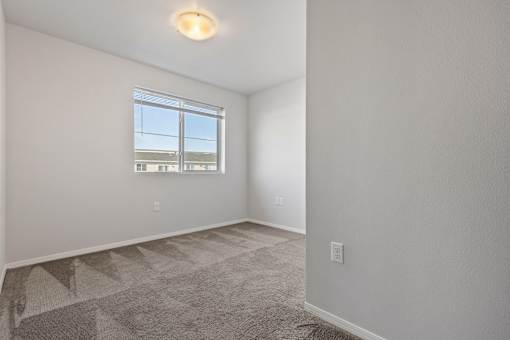 A room with a window and a carpeted floor.