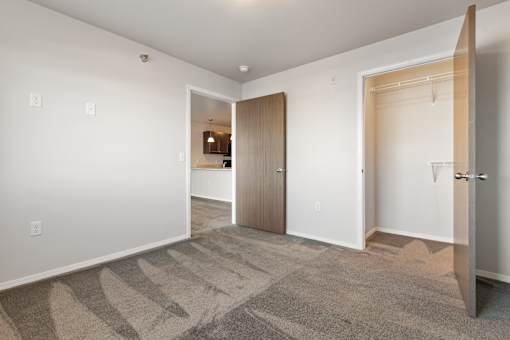 A room with a carpeted floor and two open doors.
