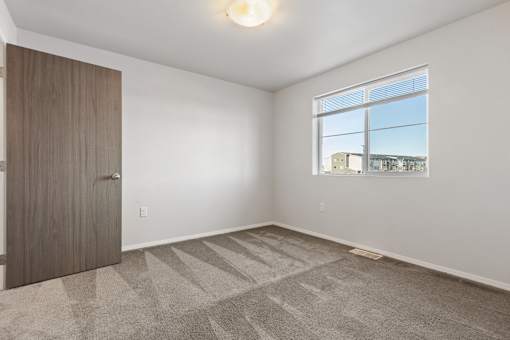 A room with a carpeted floor and a large window.