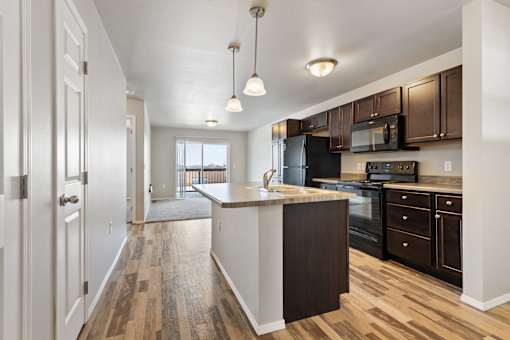 A kitchen with black appliances and brown cabinets.