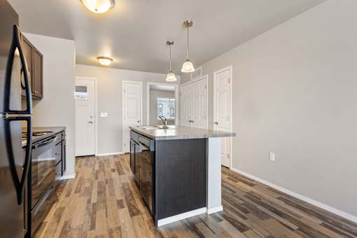 A kitchen with a black island and wooden floors.