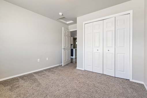 A room with white walls and a carpeted floor with a white door on the right.