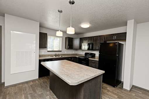 A kitchen with a black refrigerator and a wooden island.