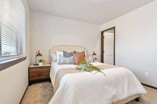 A bedroom with a bed, nightstand, and window.