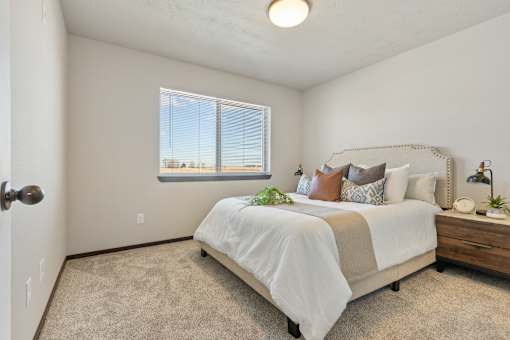 A bedroom with a bed, nightstand, and window.