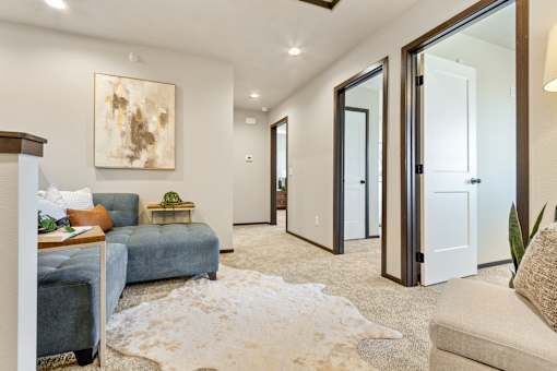 A living room with a blue couch and a white rug.