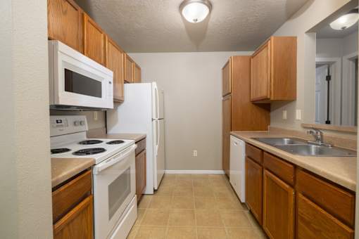 A kitchen with white appliances and wooden cabinets.