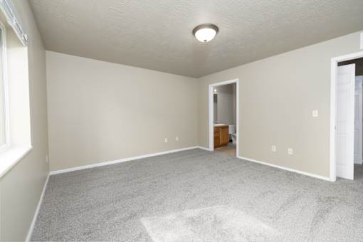 A room with a carpeted floor and a doorway leading to another room.