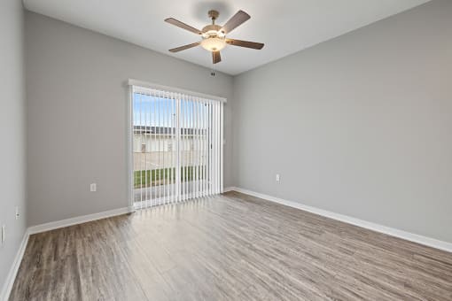an empty living room with a ceiling fan and a window