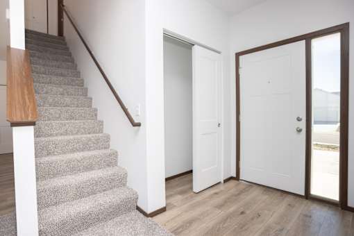 a staircase in a home with white walls and a door to a closet