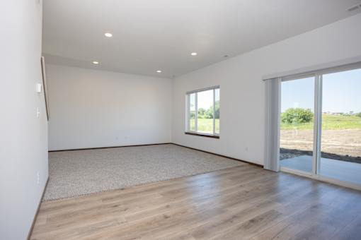 a living room with white walls and wood floors and a sliding glass door