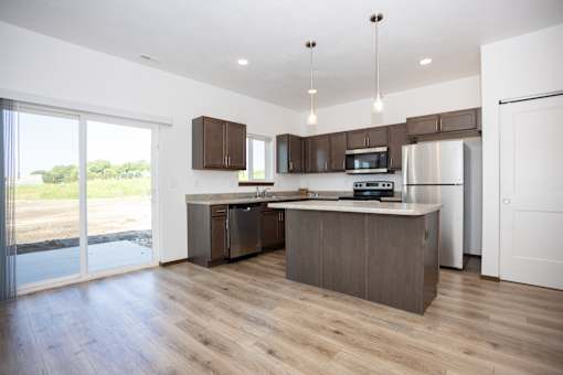 A modern kitchen with wooden floors and stainless steel appliances.