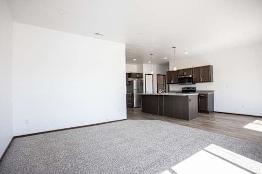 an empty living room and kitchen with white walls and wood floors