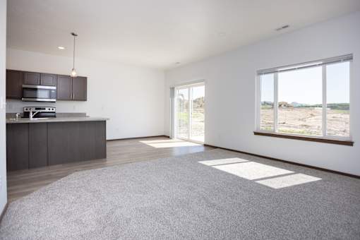 an empty living room with a kitchen and a large window