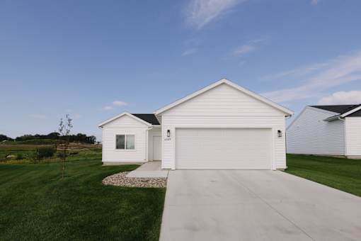 A white house with a garage door and a driveway.