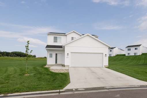 A white house with a black roof and a garage door.