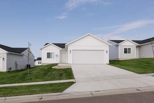 A white house with a grey roof is surrounded by other similar houses.