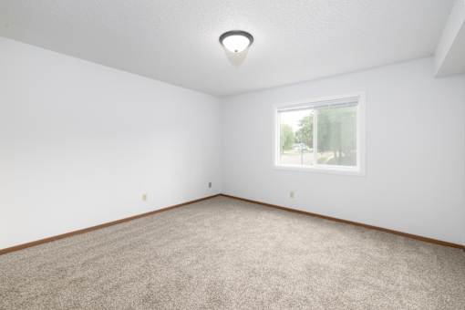 A room with a carpeted floor and a window.