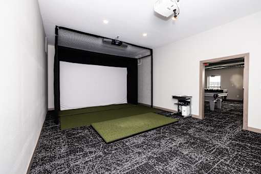 A room with a white screen and a green mat on the floor.