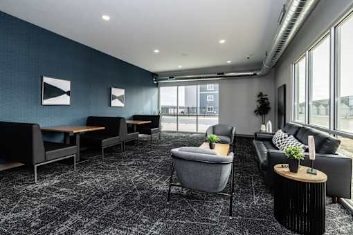 A modern living room with a grey carpet and black and white furniture.