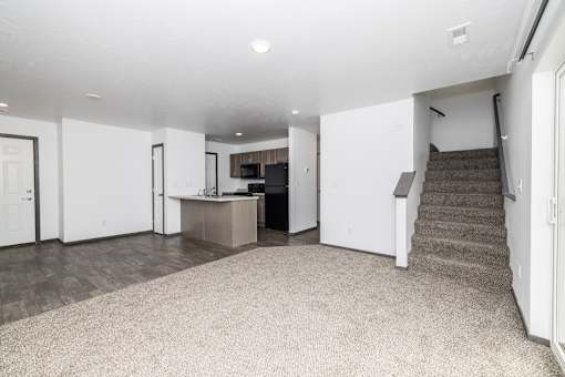 A spacious living room with a staircase leading to the upper floor.