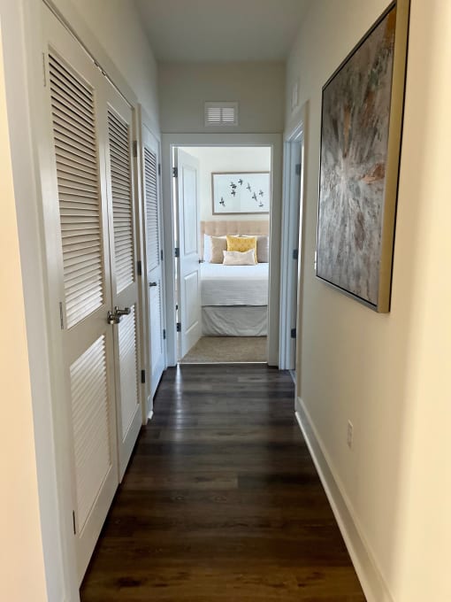 a narrow hallway with a bedroom in the background and a door to a room with