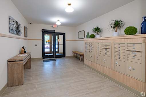 A hallway with a bench, a wooden table, and a row of lockers.