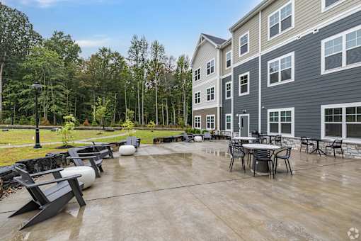 A patio area with a table and chairs is shown in front of a building.