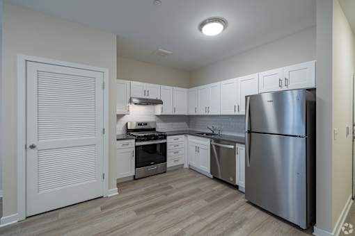A kitchen with a stainless steel refrigerator, stove, and cabinets.