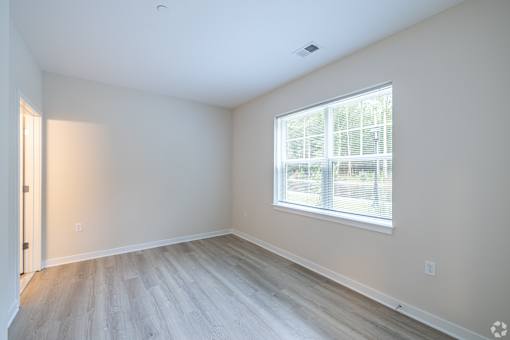 A room with a window and wooden flooring.