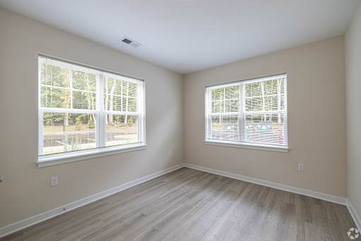 A room with two windows and wooden flooring.