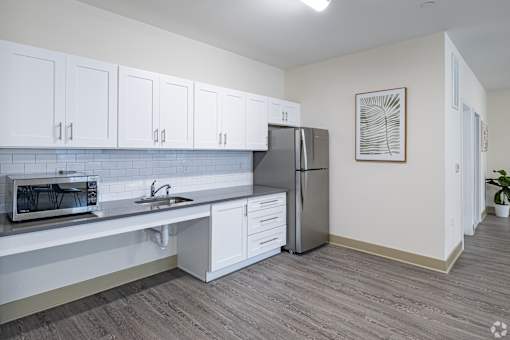 A kitchen with white cabinets and a grey refrigerator.