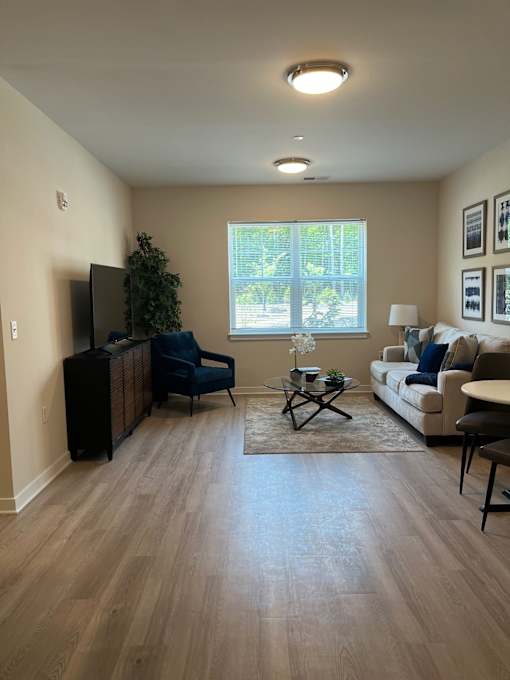 A living room with a couch, chair, and television.