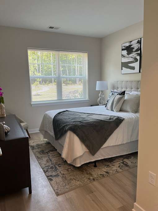 A bedroom with a bed, nightstand, and window.