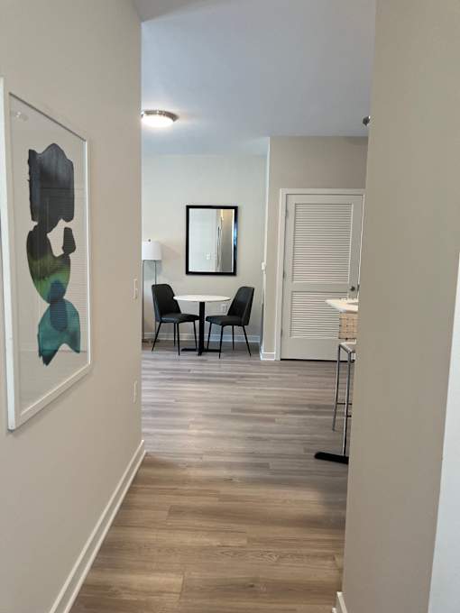 A hallway with a chair and a table in the distance.