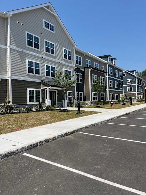 A parking lot in front of a multi-story apartment building.