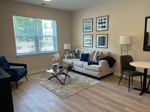 A living room with a couch, chair, and pictures on the wall.