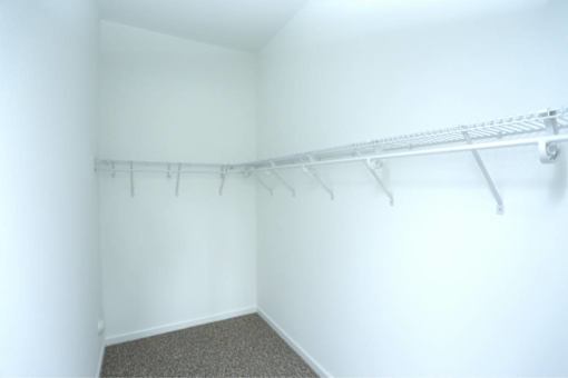 a white closet with a white wall and a white rack on the wall