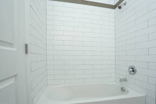 a white bathroom with a white tub and white tiles