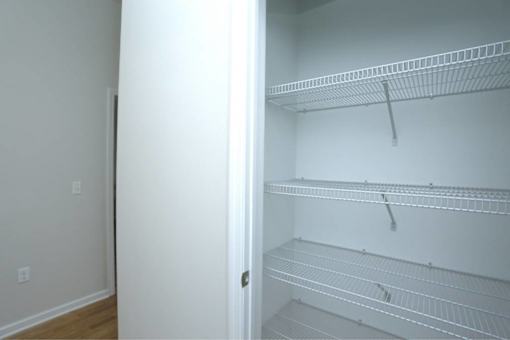 an empty closet with white shelves and a white door