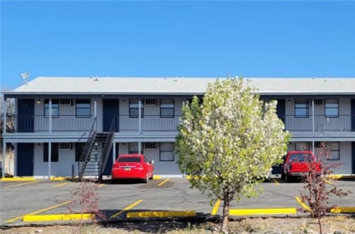 an apartment building with cars parked in a parking lot