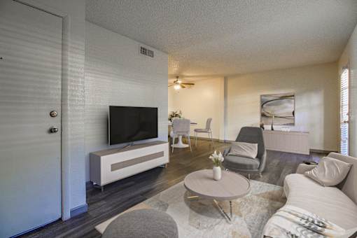 A living room with a grey couch, a white coffee table, and a television.