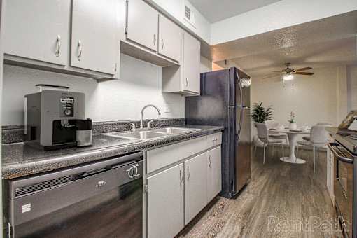 A kitchen with a refrigerator, sink, and stove.