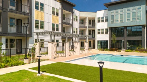 an exterior view of an apartment building with a swimming pool at Birdie on Woodland Greens, Austin