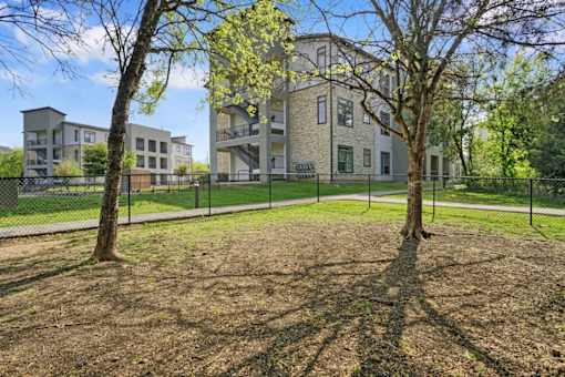 a yard with two trees and a fence in front of a building at Radius on Grove, Austin
