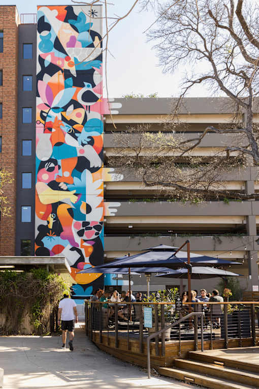 Outdoor courtyard with colorful mural and dining area at THE'68 Apartments, Texas